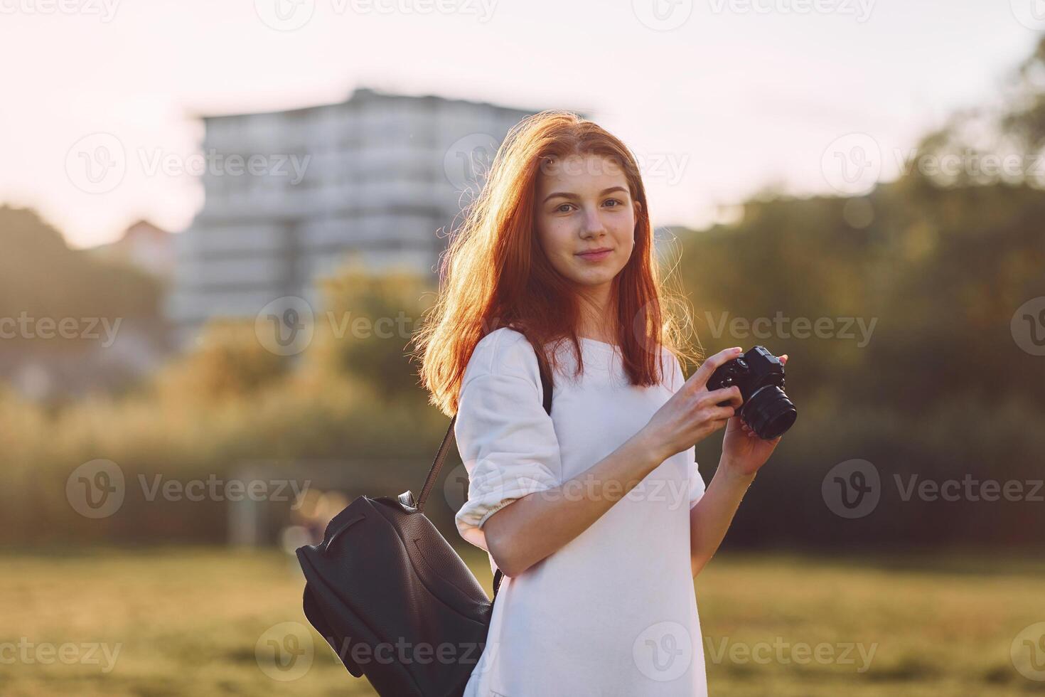 Holding camera.,Young girl is on the field at sunny daytime having nice weekend photo