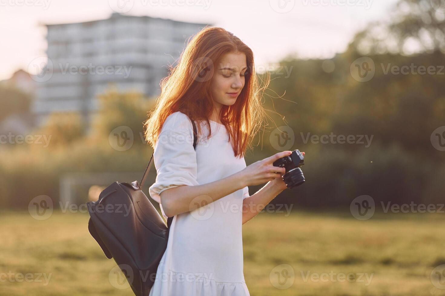 Holding camera on . Young girl is on the field at sunny daytime having nice weekend photo