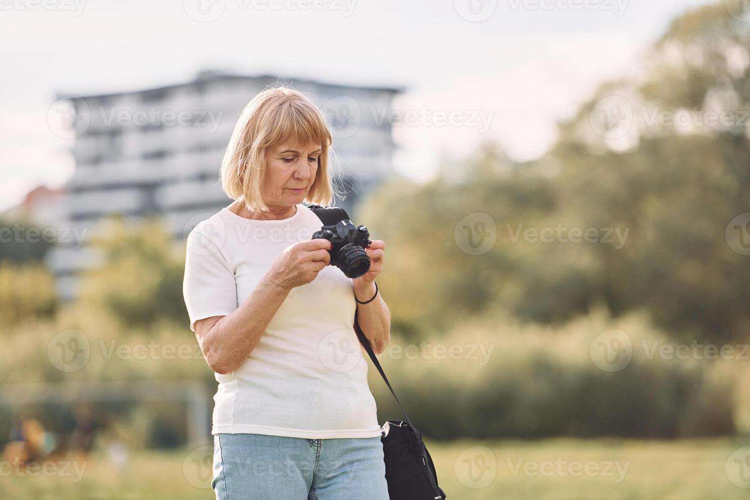 Photographer with a cameras. Senior woman having nice weekend outdoors on the field at sunny day photo