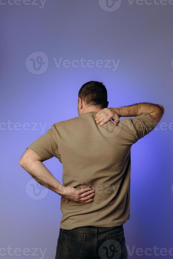 man experiences back neck pain due to age-related changes, osteochondrosis, herniated discs or chronic spinal diseases. Prevention of spinal problems, therapeutic exercises, physiotherapy. photo