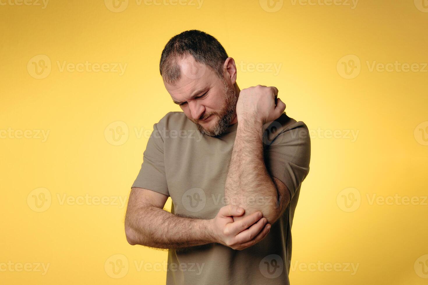 Man suffers from elbow pain due to negative impact of long-term computer work, bad posture, uncomfortable workplace. Concept of comfortable work space to avoid joint pain and health problems photo