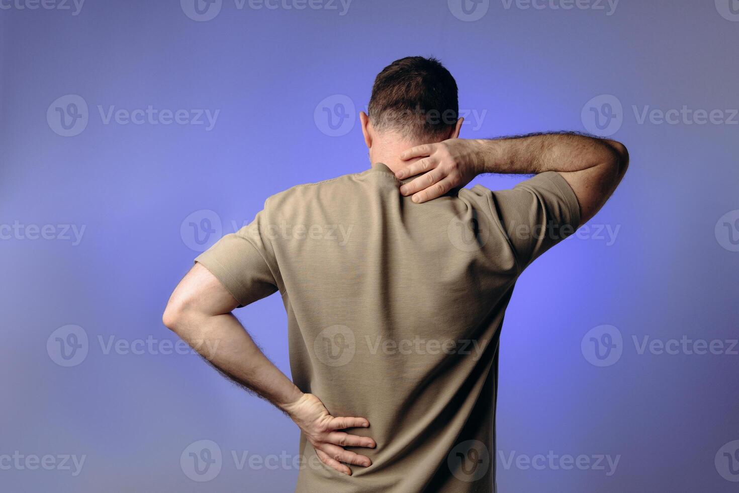 man experiences back neck pain due to age-related changes, osteochondrosis, herniated discs or chronic spinal diseases. Prevention of spinal problems, therapeutic exercises, physiotherapy. photo