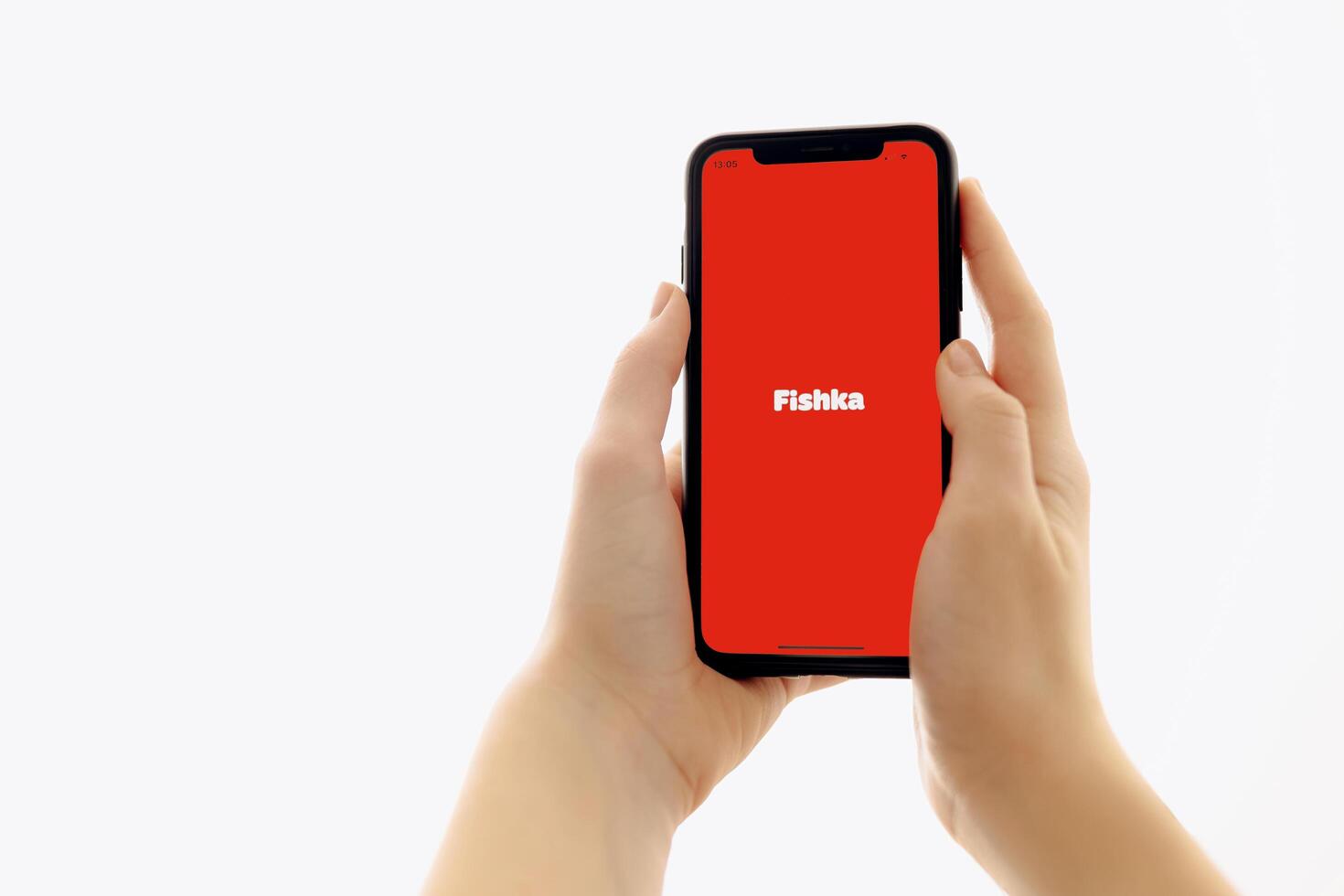 Zaporizhia, Ukraine - January 10, 2025. A woman holds an iPhone with the Fischka app logo on the screen while using a mobile app for business at home. white background photo