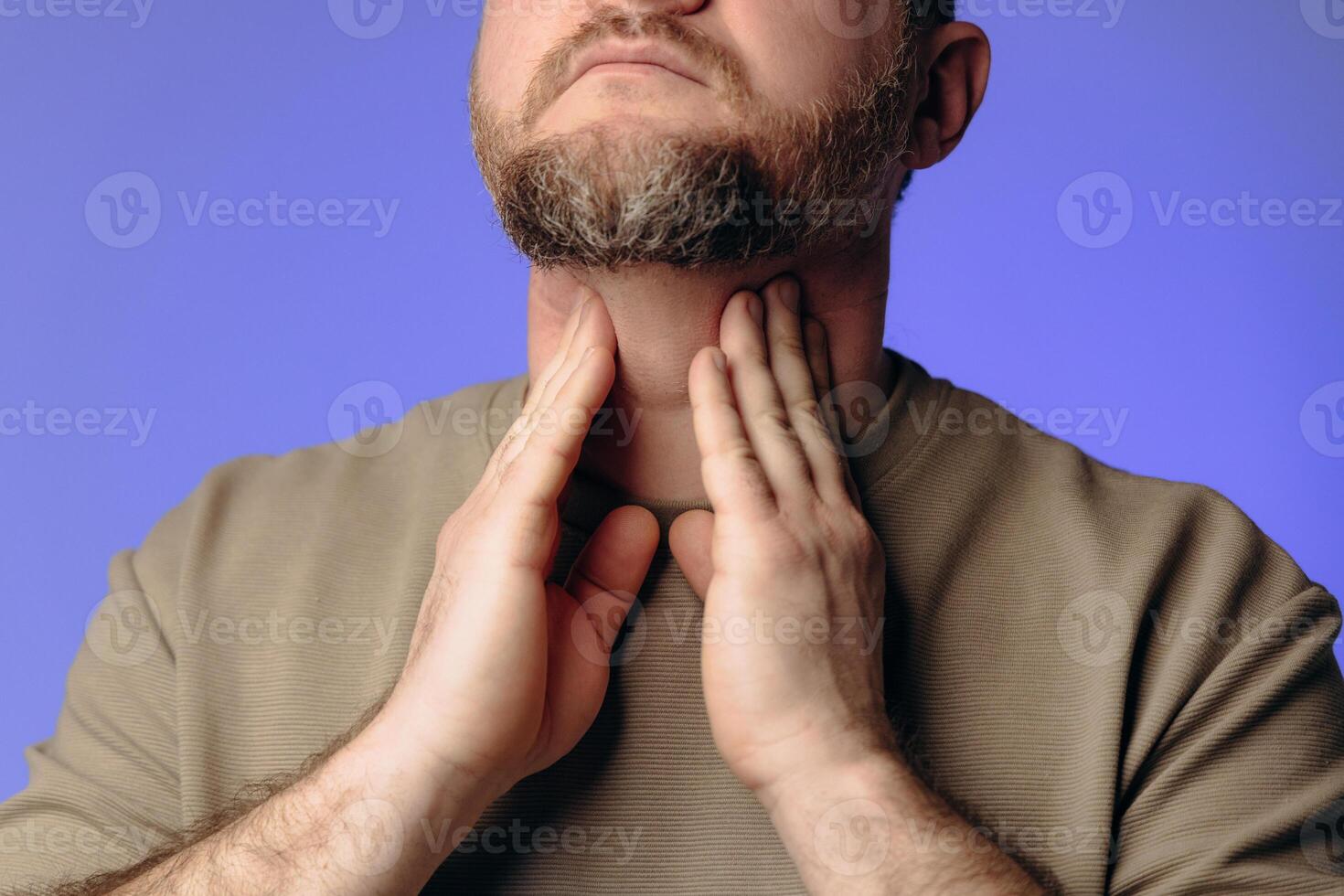 A man has a sore throat and neck due to a cold. The man holds his hand to his throat. He experiences discomfort when swallowing. The concept of viral diseases photo