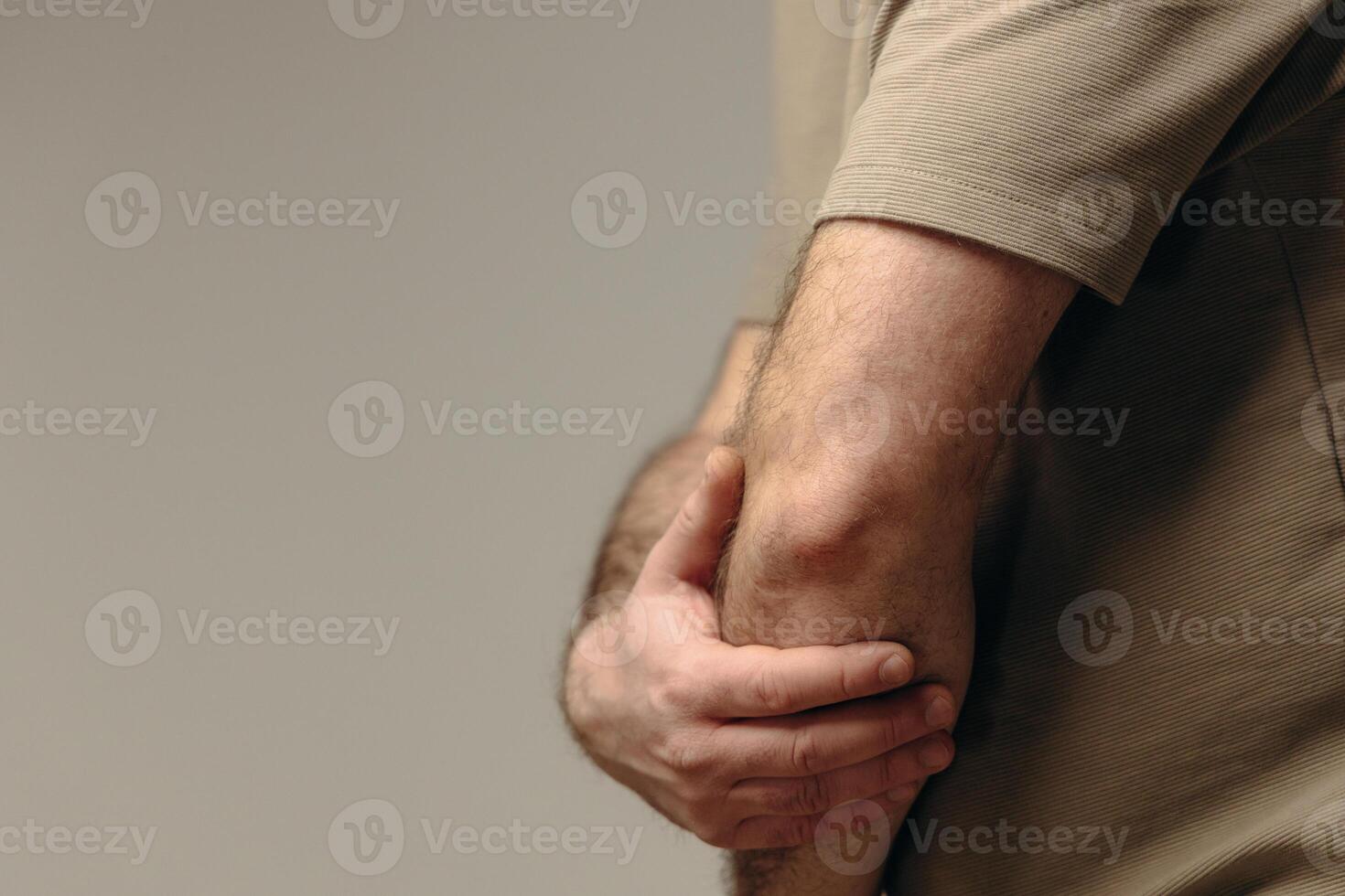 Man suffers from elbow pain due to negative impact of long-term computer work, bad posture, uncomfortable workplace. Concept of comfortable work space to avoid joint pain and health problems photo