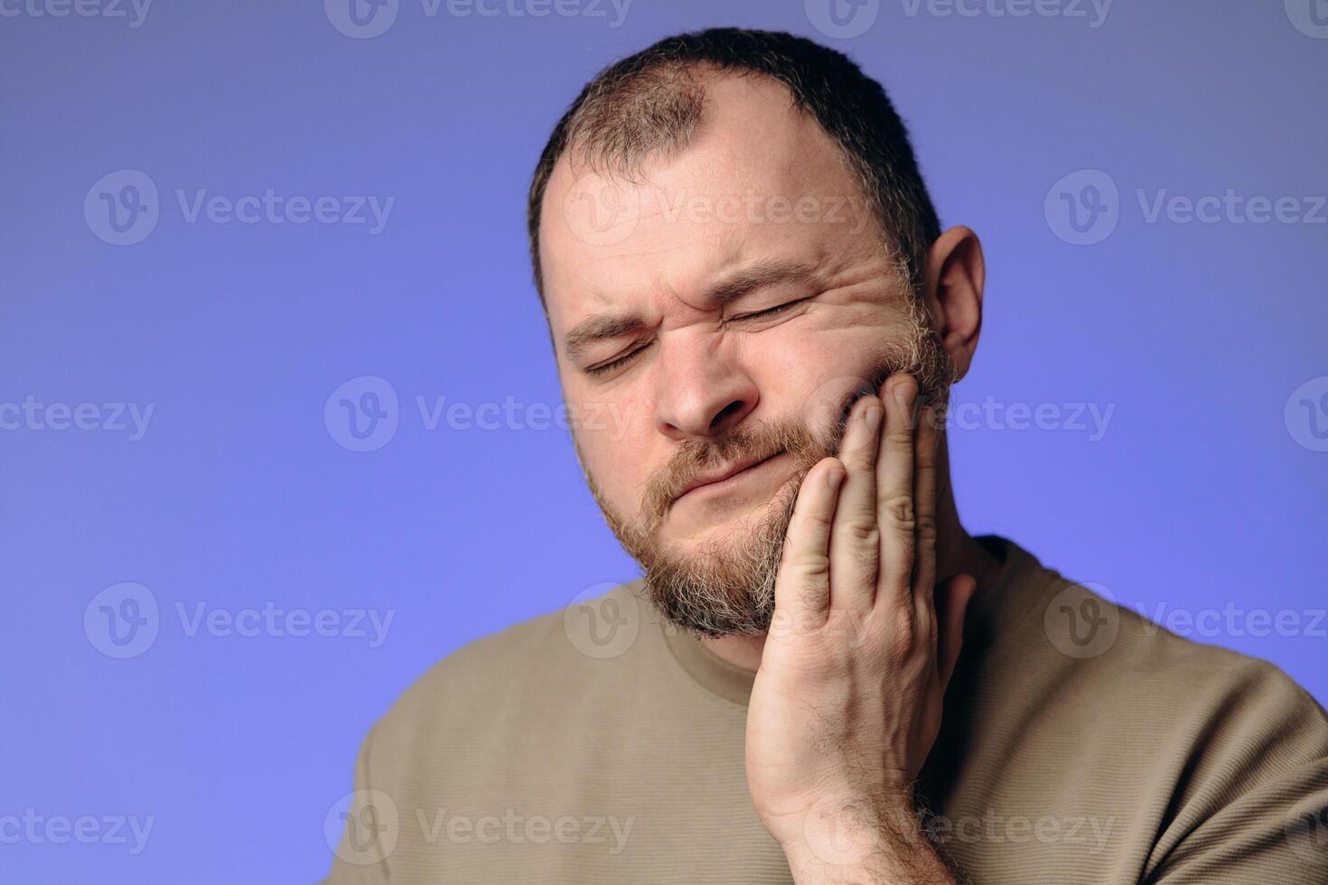 man holding his cheek with his hand experiencing severe toothache. Toothache is the most severe pain in a person. Teeth require careful care. They play an important role in a person's life photo