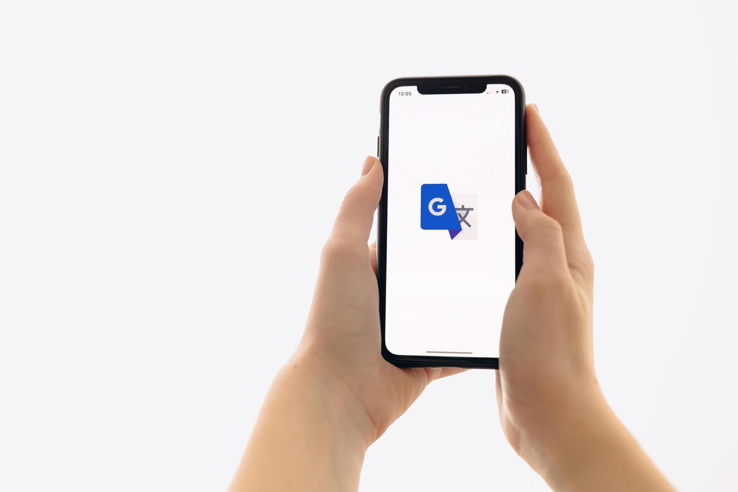 Zaporizhia, Ukraine - January 10, 2025. A woman holds an iPhone with the Google Translate app logo on the screen while using a mobile app for business at home. white background photo