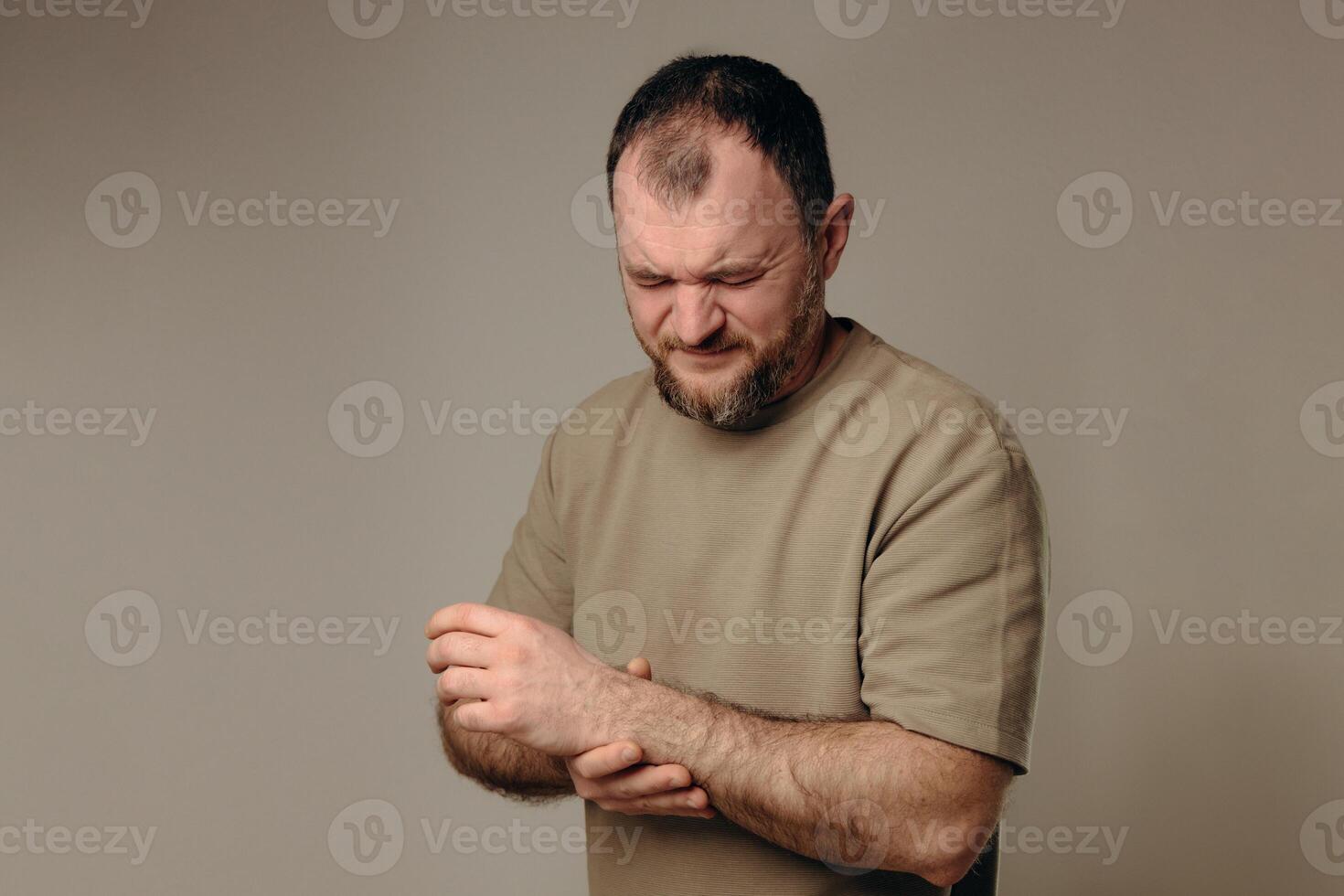 A man holds his wrist in pain. The hand tightly clasps the affected area, emphasizing the soreness and need for support. Pain and suffering in the wrist interfere with professional activities. photo