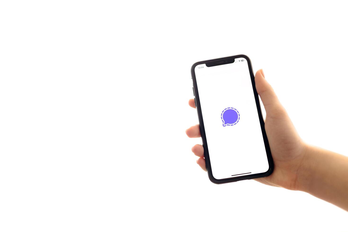 Zaporizhia, Ukraine - January 10, 2025. A woman holds an iPhone with the Signal app logo on the screen while using a mobile app for business at home. white background photo