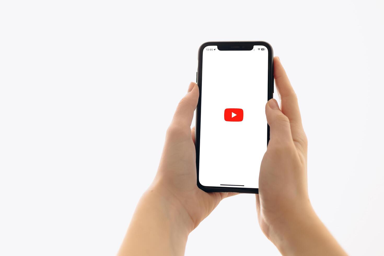 Zaporizhia, Ukraine - January 10, 2025. A woman holds an iPhone with the YouTube app logo on the screen while using a mobile app for business at home. white background photo