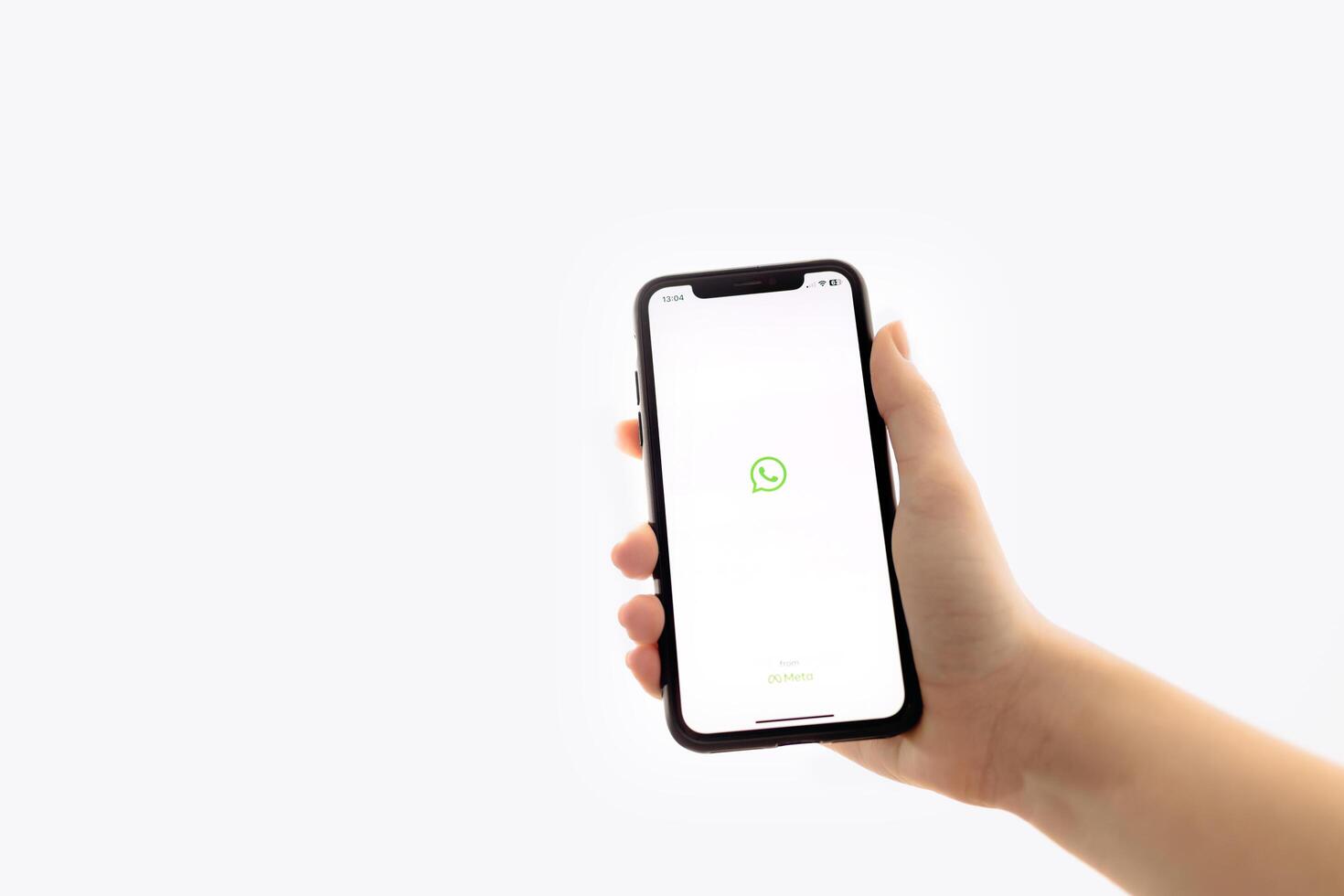 Zaporizhia, Ukraine - January 10, 2025. A woman holds an iPhone with the WhatsApp app logo on the screen while using a mobile app for business at home. white background photo