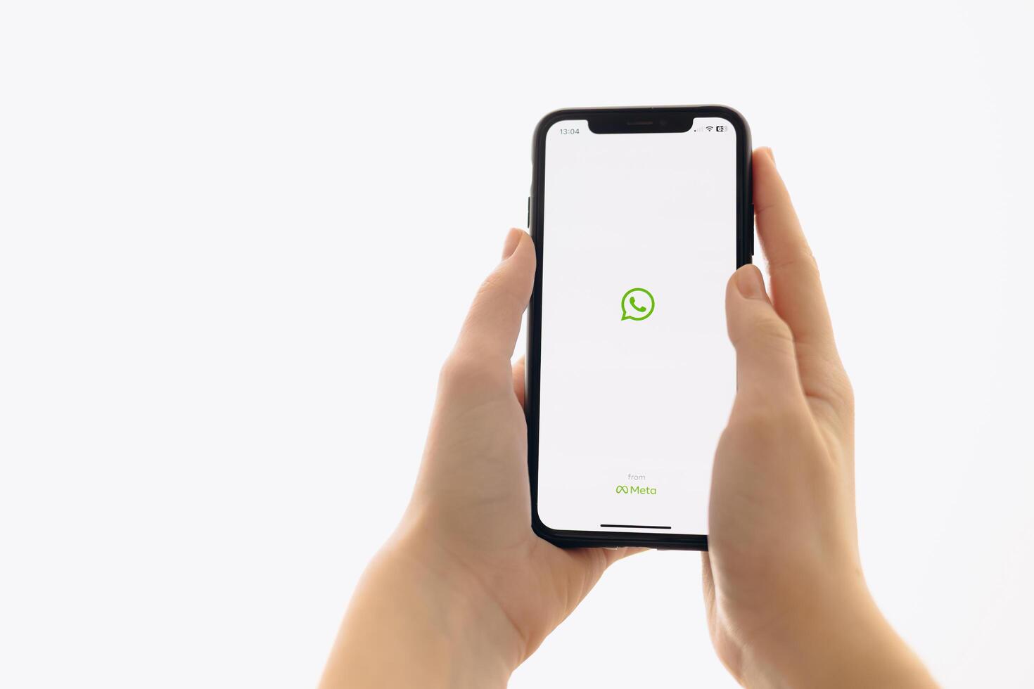 Zaporizhia, Ukraine - January 10, 2025. A woman holds an iPhone with the WhatsApp app logo on the screen while using a mobile app for business at home. white background photo