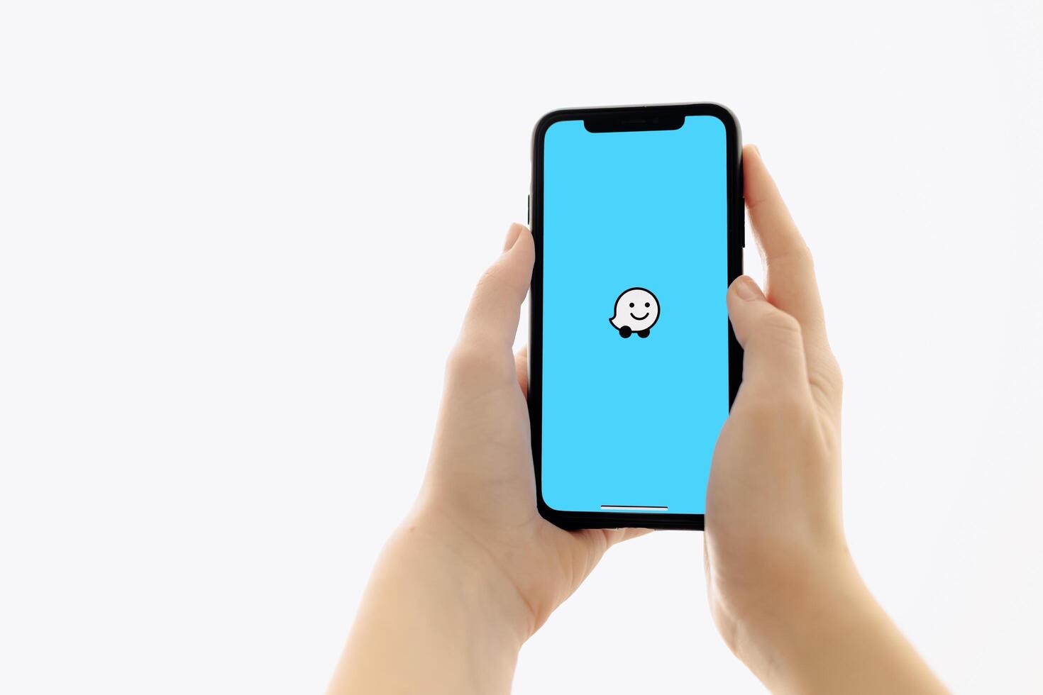 Zaporizhia, Ukraine - January 10, 2025. A woman holds an iPhone with the Waze app logo on the screen while using a mobile app for business at home. white background photo