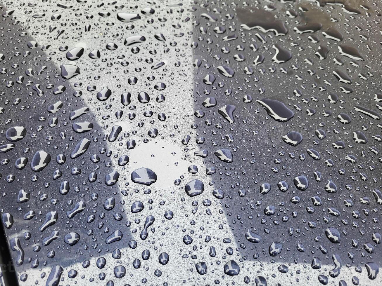 Raindrops and reflections on a dark car in rainy weather photo