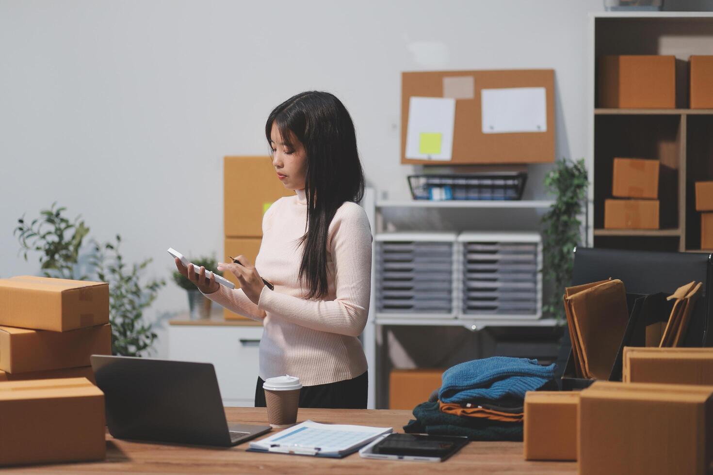 A woman standing in front of a desk with boxes and a laptop photo