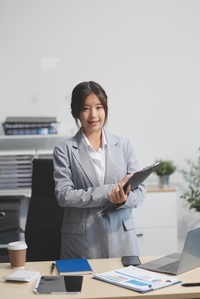 Asian businesswoman standing at desk with laptop photo
