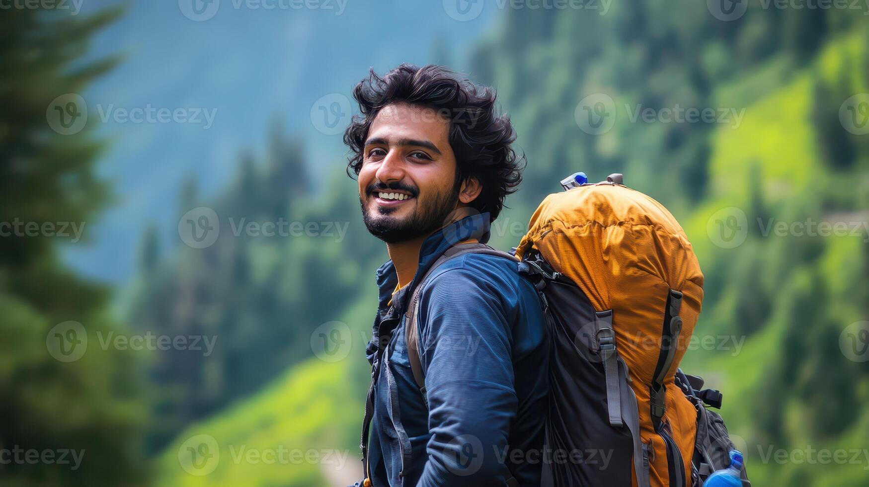 A man with a backpack smiles while standing in the mountains photo