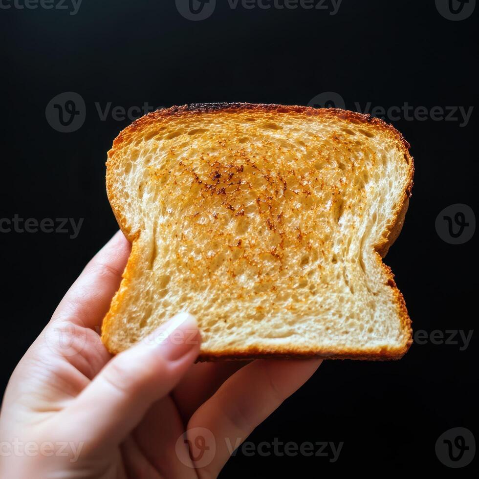 A person holding a piece of toast in their hand photo