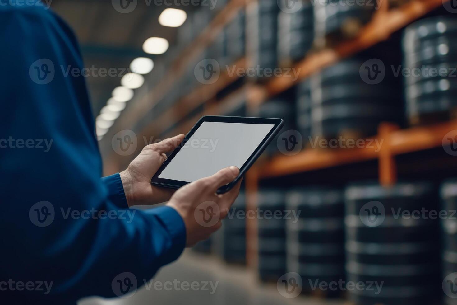 Worker using tablet in a warehouse to manage inventory of barrels during the daytime photo
