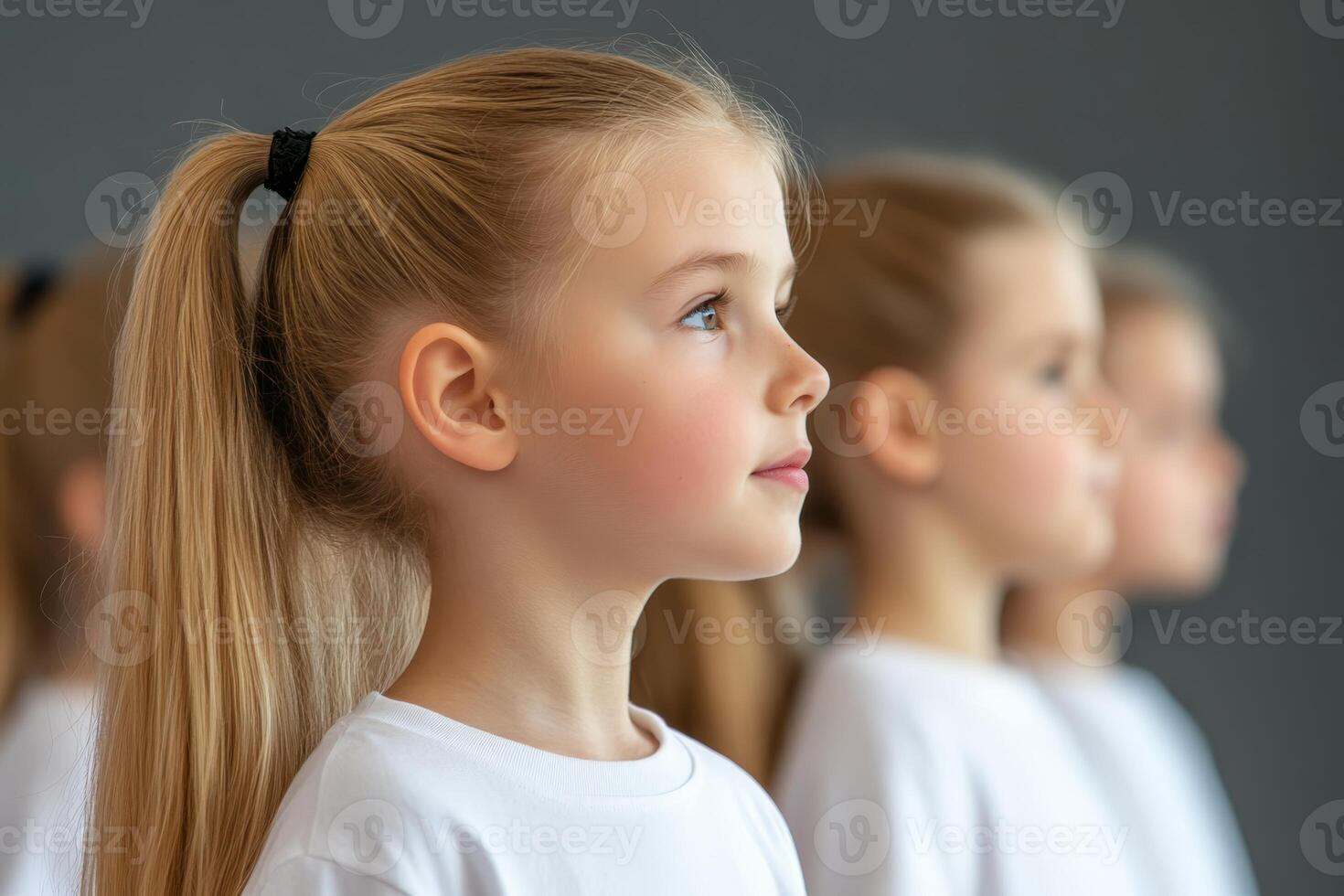 Young girls standing in line with focused expressions during a dance rehearsal in a studio photo
