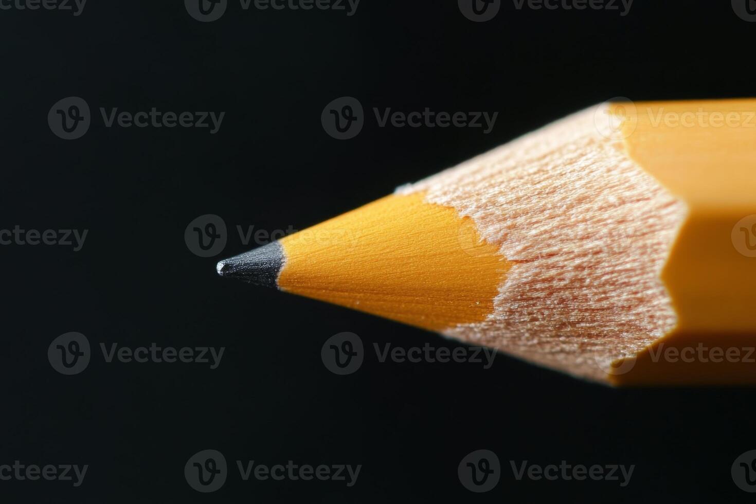 Close-up of a sharpened yellow pencil against a dark background emphasizing its fine tip and texture photo