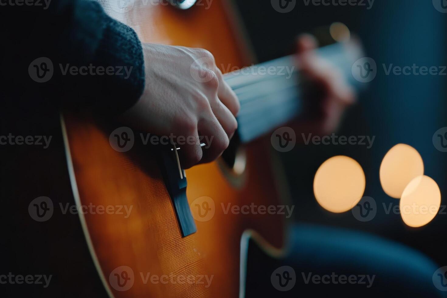 Hands playing an acoustic guitar amidst softly glowing candles in a warm ambiance setting photo