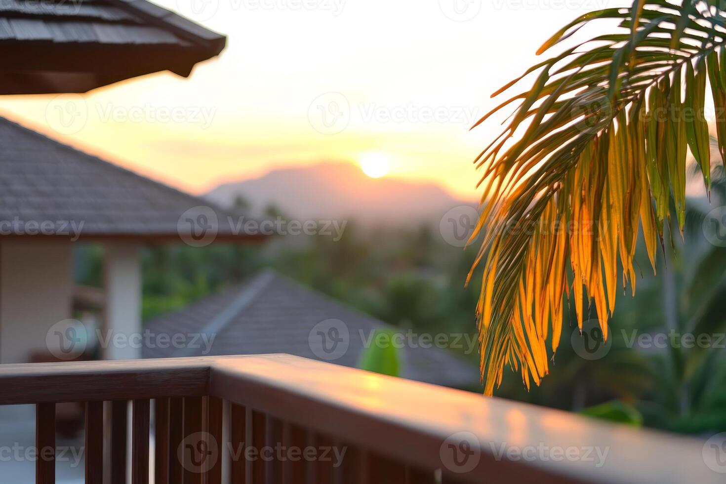 Sunset view from a balcony with palm leaves and mountains in the distance creating a tranquil atmosphere photo