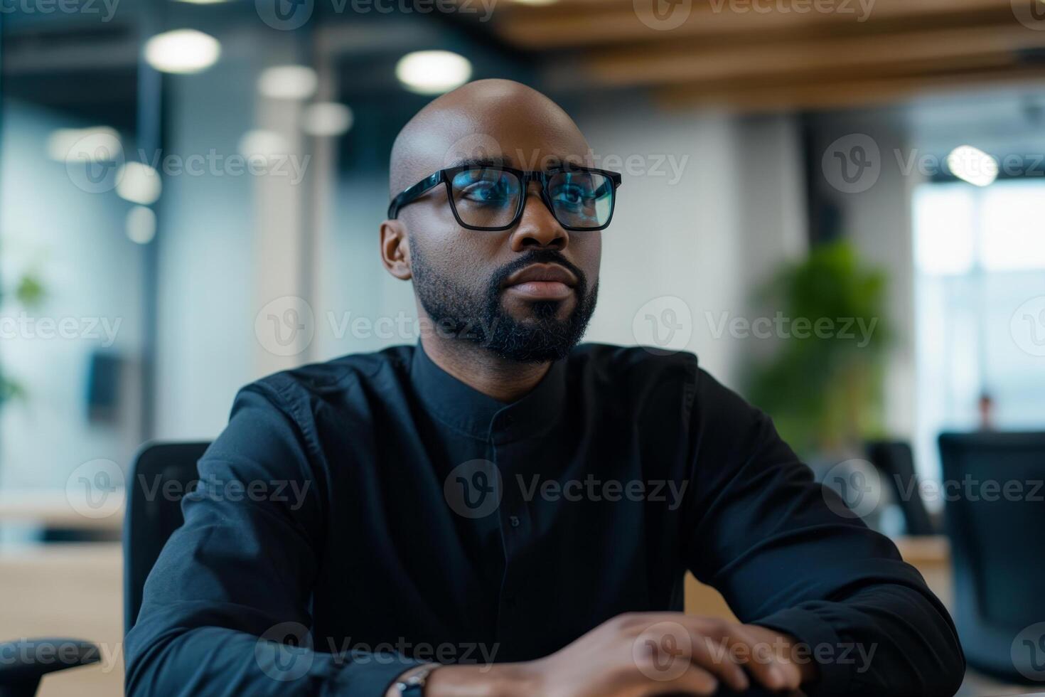 Professional man working intently at a modern office desk during daylight hours in a collaborative workspace photo