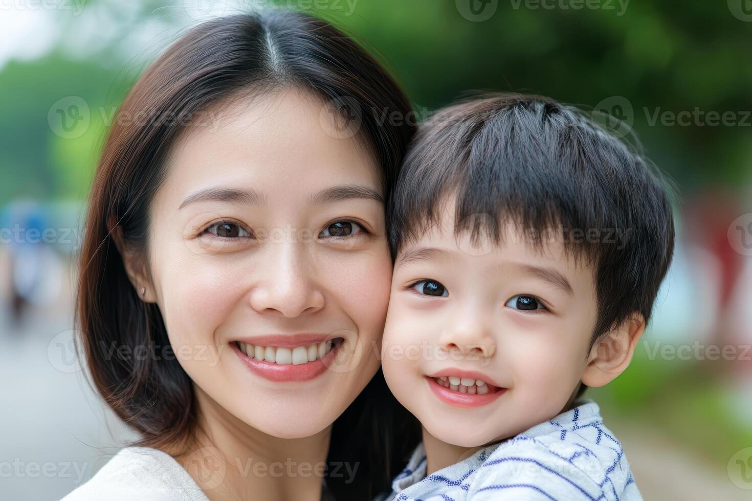Smiling mother and son enjoying a sunny day outdoors in a park setting while posing for a cheerful moment photo