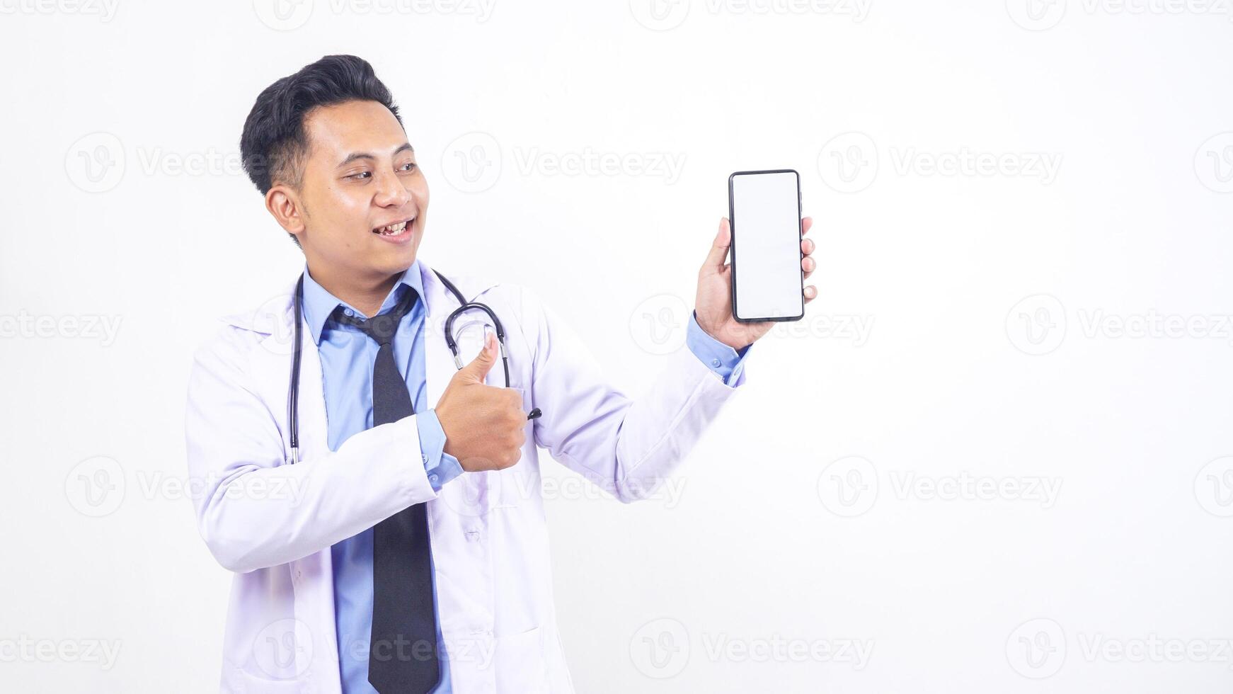 Asian Male Doctor Showing Blank Screen Mobile Phone Mock Up and Raising Thumb Up on White Background photo