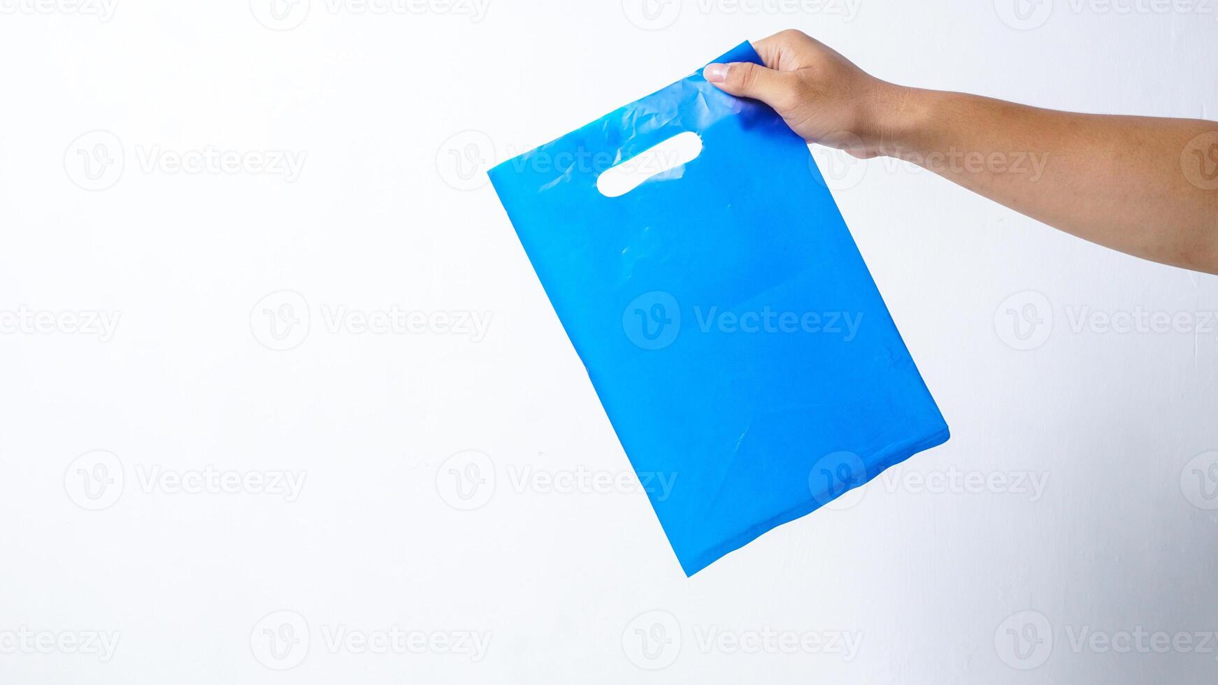 Hand Holding Blue Plastic Bag Mock Up with Handle on White Background photo