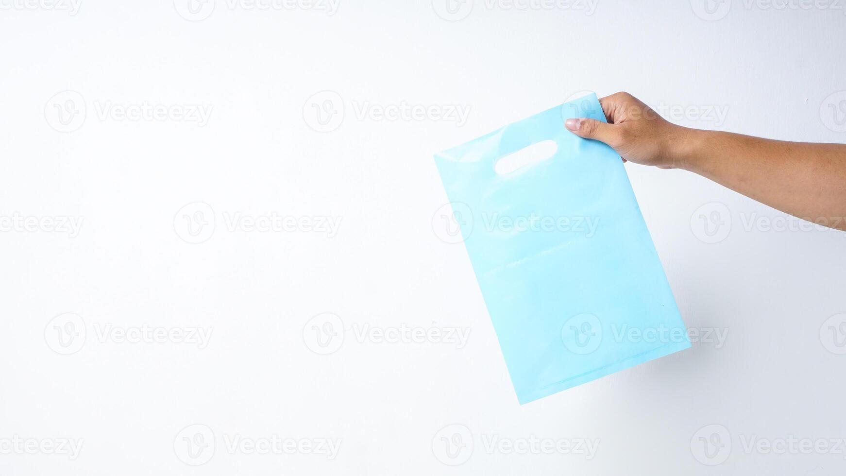Hand Holding Light Blue Plastic Bag Mock Up on White Background photo