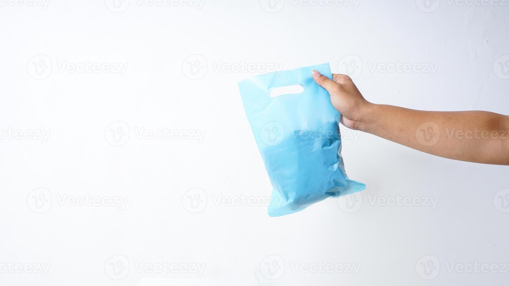 Hand Holding Filled Light Blue Plastic Bag Mock Up on White Background photo