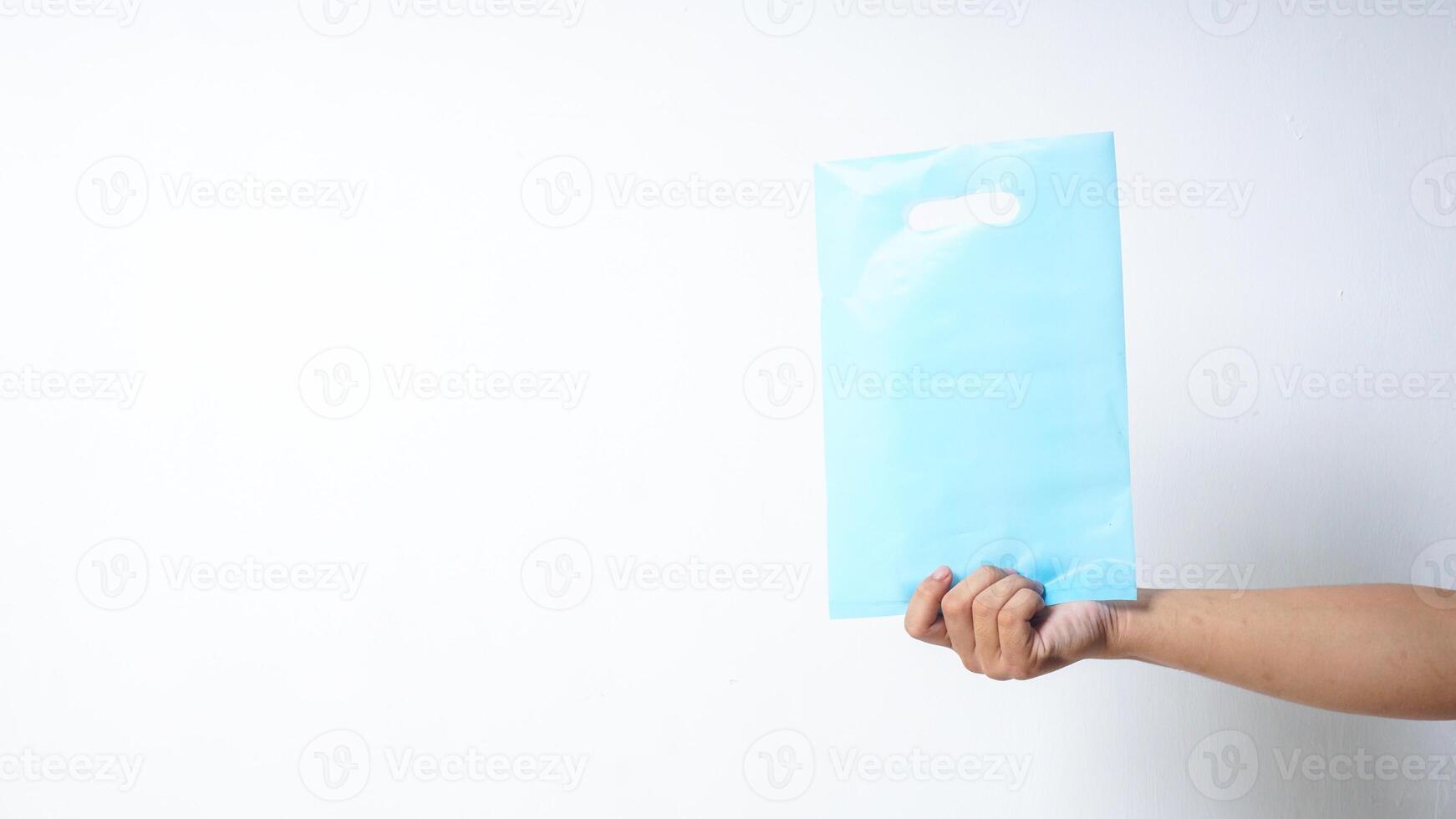 Hand Showing Blank Light Blue Plastic Bag with Handle on White Background photo