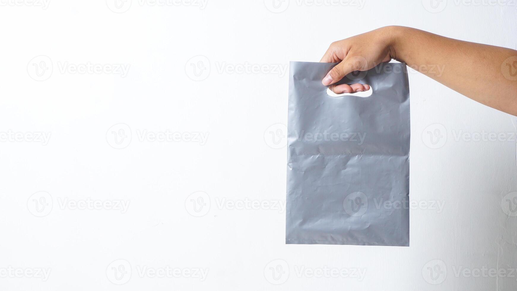 Hand Carrying Empty Gray Plastic Bag on White Background photo