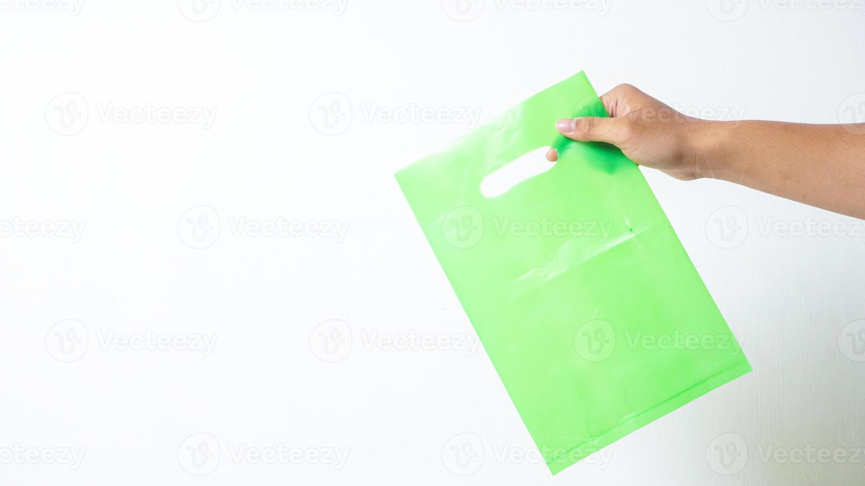 Hand Shows Blank Green Plastic Bag Mock Up on White Background photo