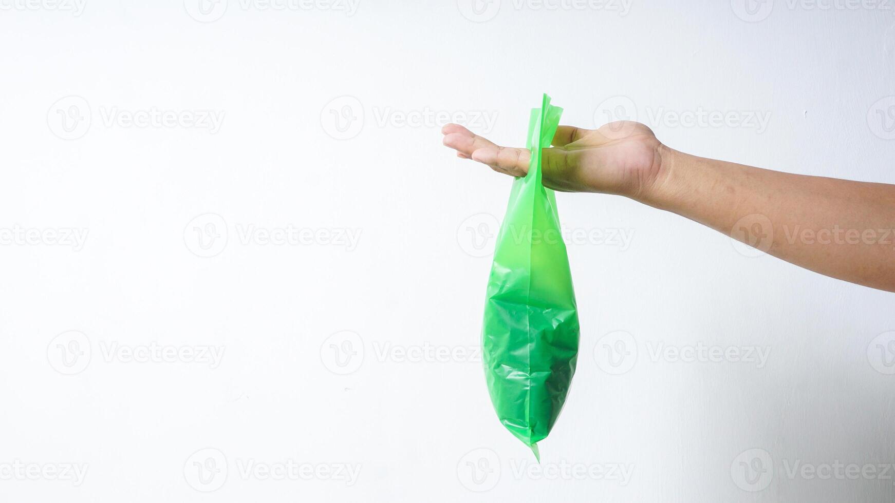 Hand Carrying Filled Green Plastic Bag with Copy Space on White Background photo