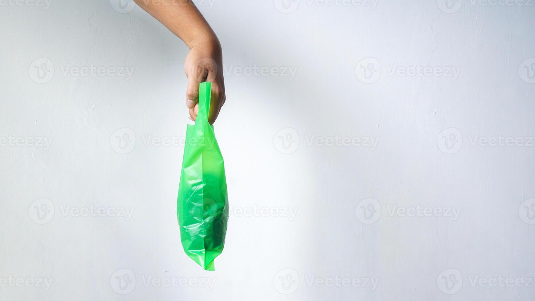 Side View of Hand Carrying Green Plastic Bag with Copy Space on White Background photo