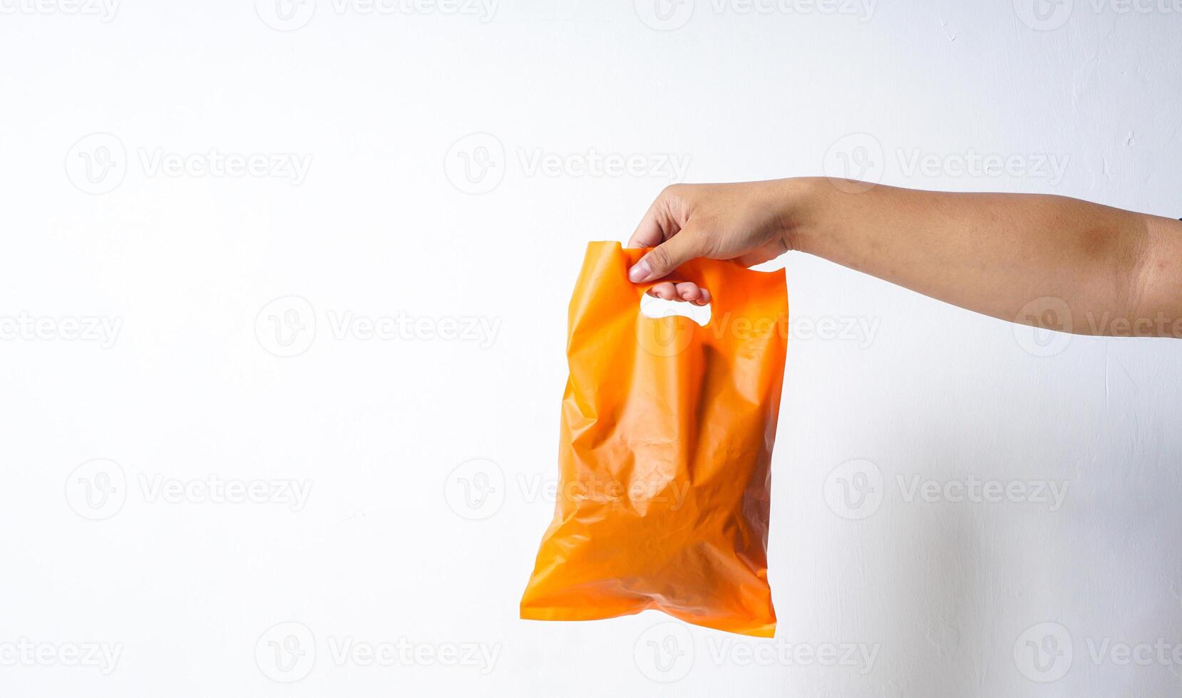Hand Holding Orange Plastic Bag Mock Up on White Background photo