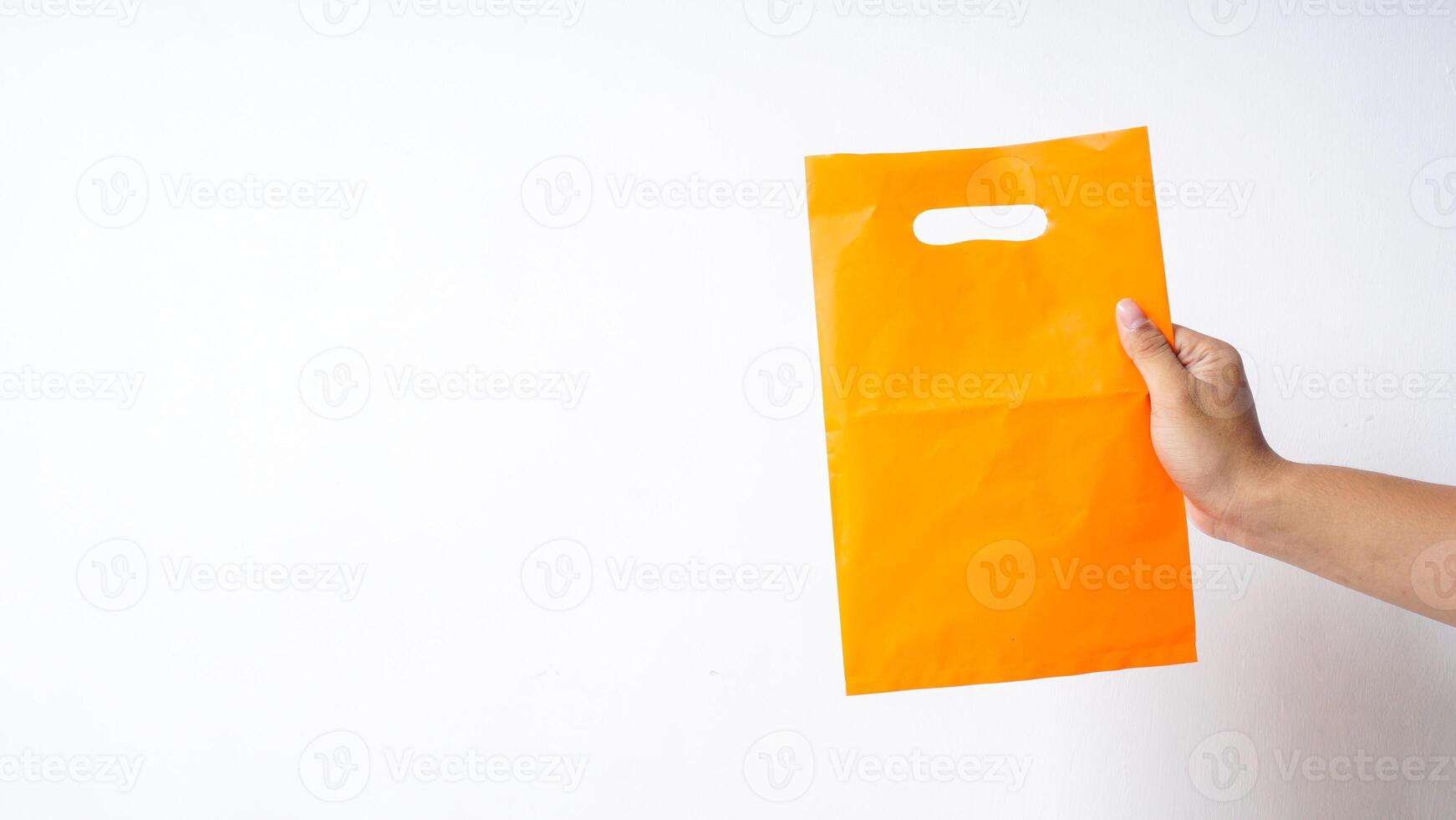 Hand Showing Blank Orange Plastic Bag Mock Up with Handle on White Background photo