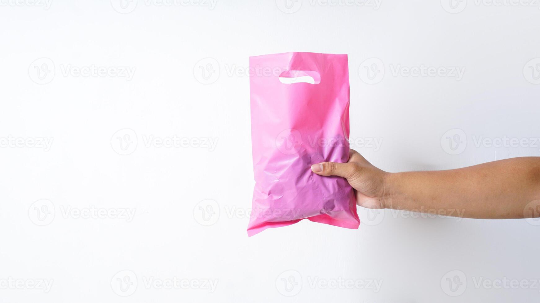 Hand Holding Filled Pink Plastic Bag with Handle on White Background photo
