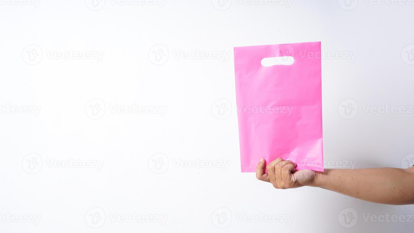 Hand Shows Blank Pink Plastic Bag Mock Up with Copy Space on White Background photo
