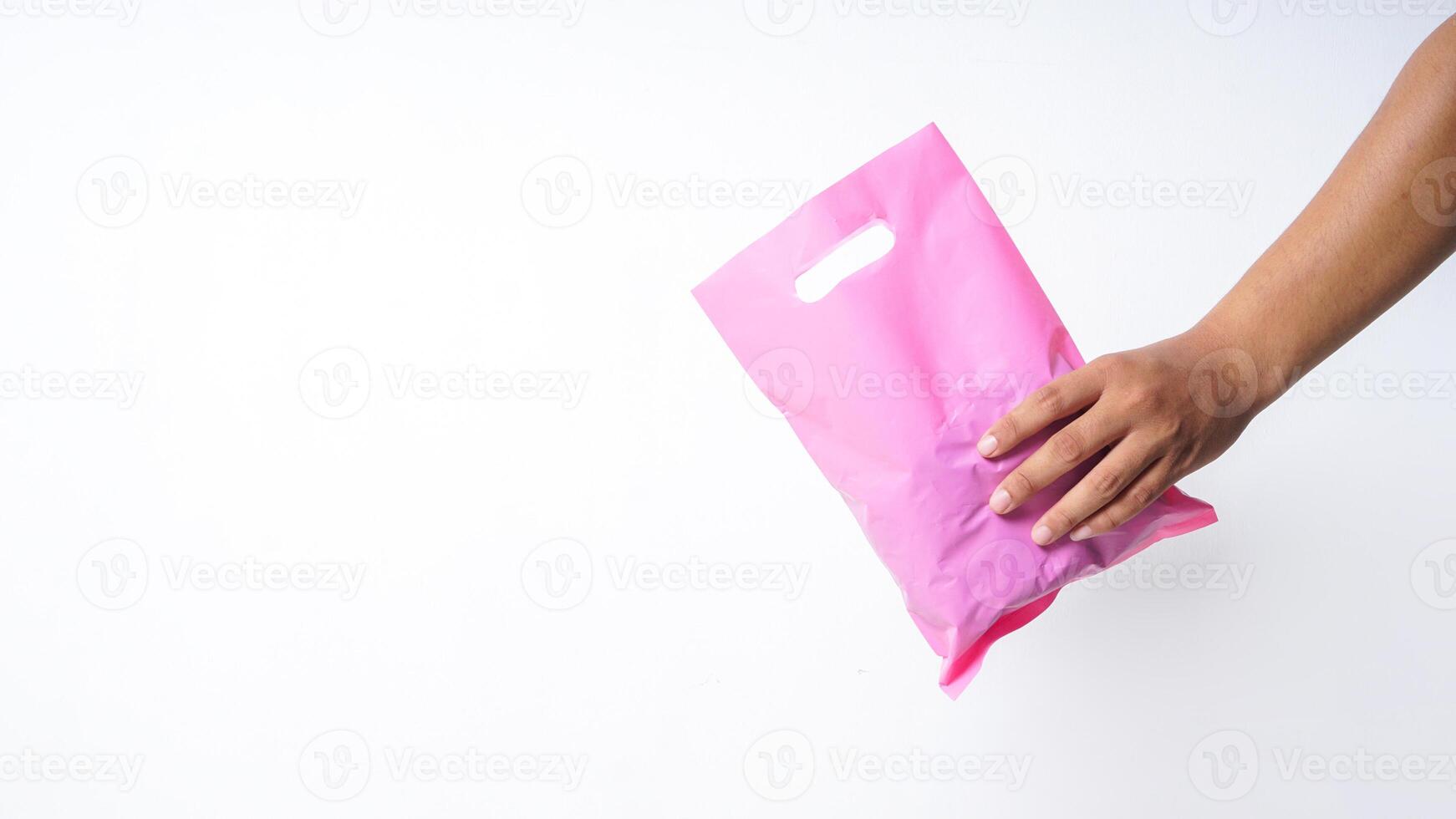 Hand Holding Filled Pink Plastic Bag Mock Up with Copy Space on White Background photo