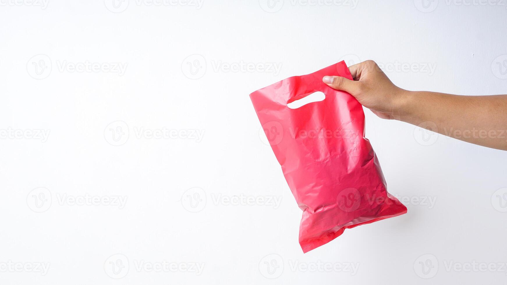 Hand Holding Filled Red Pink Plastic Bag on White Background photo