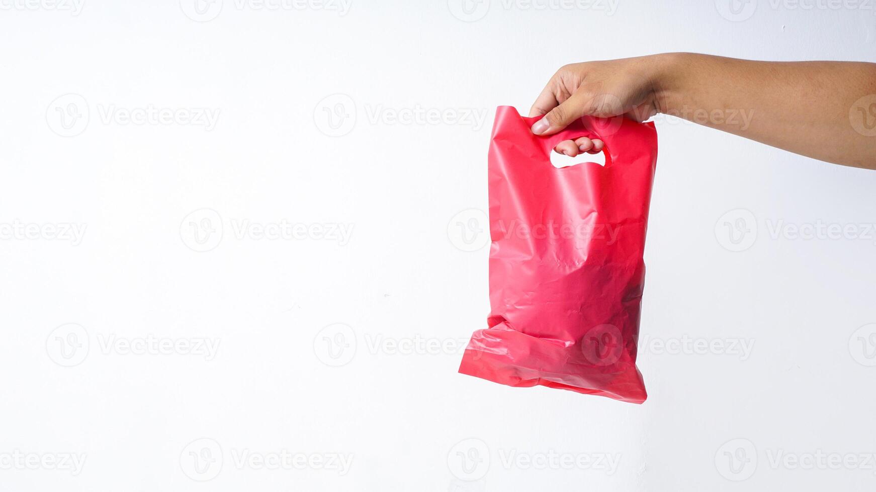 Hand Carrying Filled Red Pink Plastic Bag on White Background photo