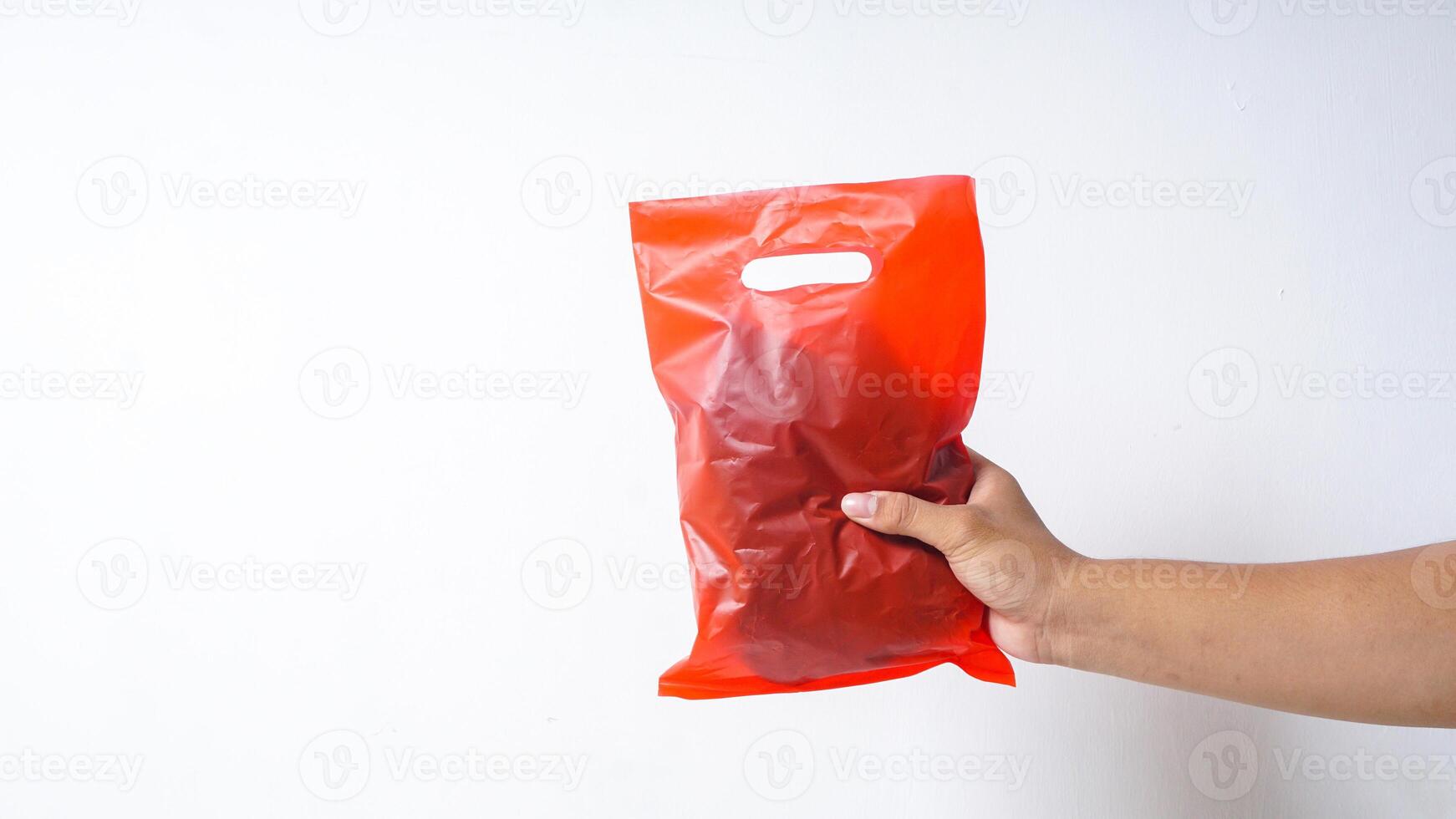 Hand Holding Used Red Plastic Bag on White Background photo