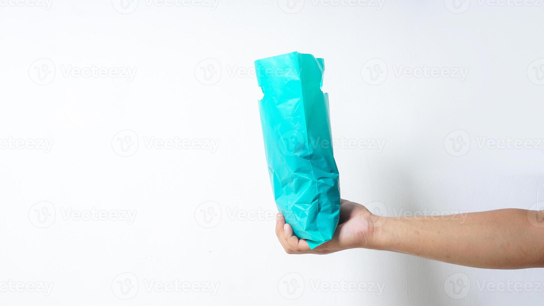 Side View of Hand Holding Filled Turquoise Plastic Bag on White Background photo