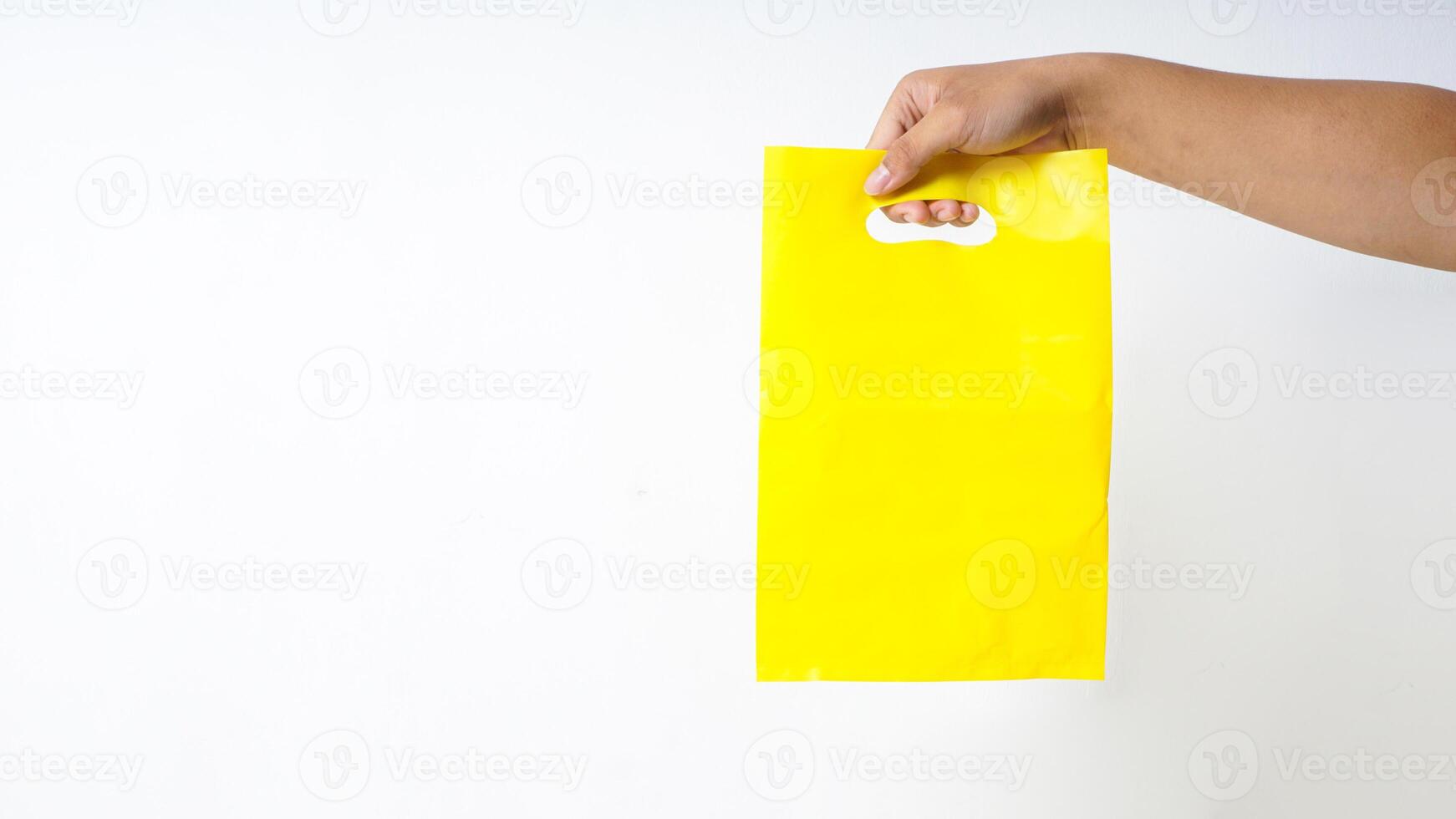 Hand Carrying Yellow Plastic Bag Mock Up on White Background photo