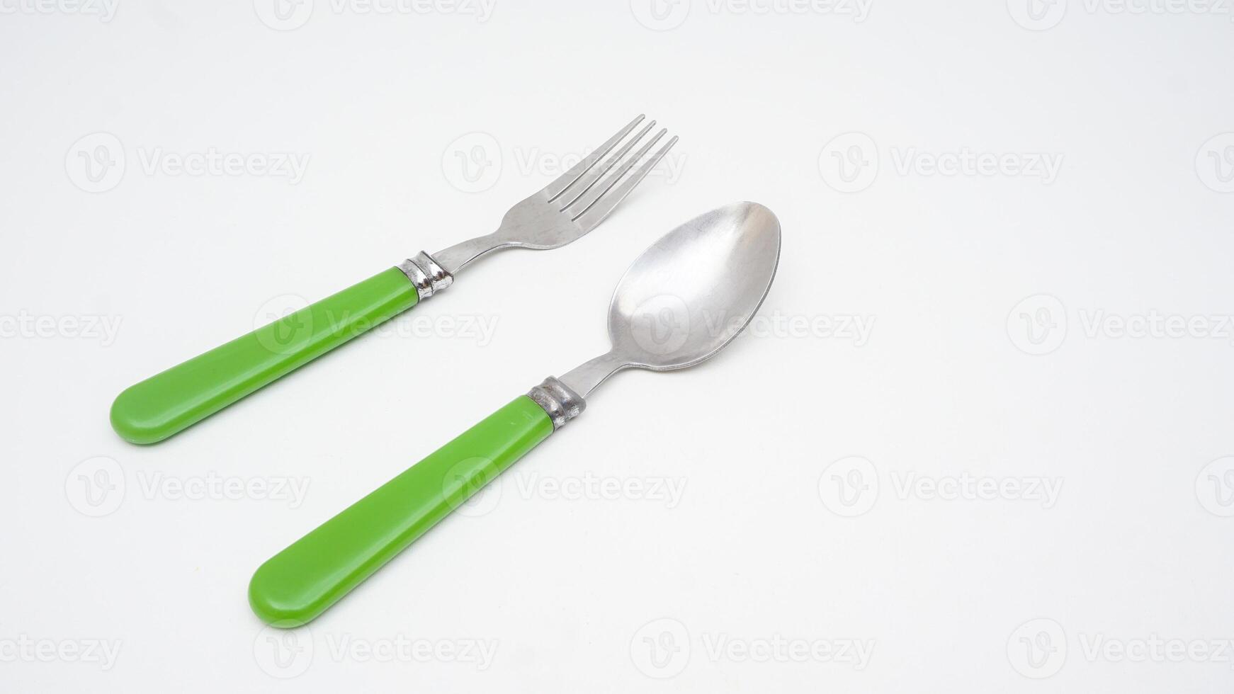 A pair of stainless steel spoon and fork with green handle isolated on white background photo