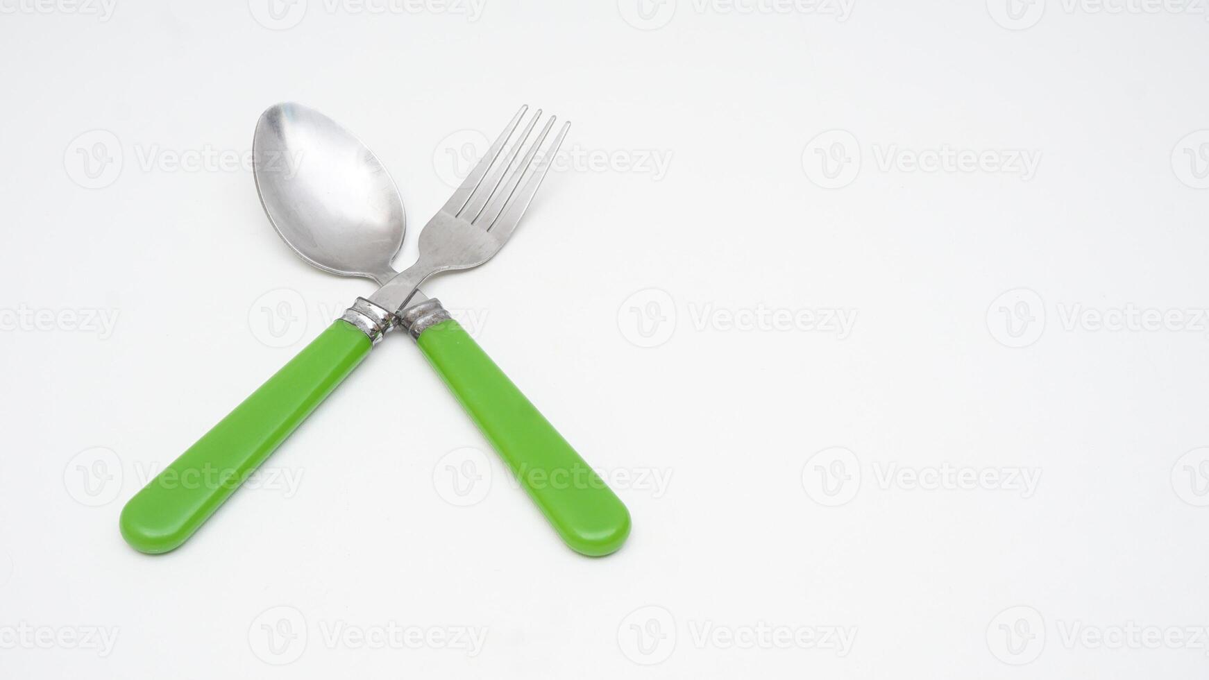 Stainless steel spoon and fork with green handle isolated on white background photo